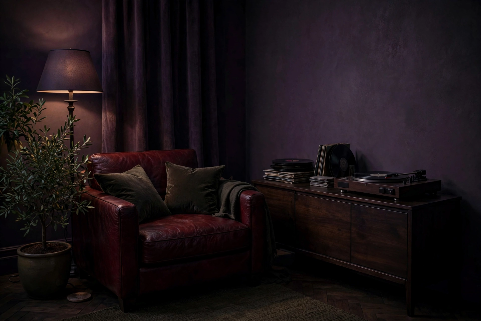 Listening room in deep muted E minor colors — plum walls, an oxblood leather chair, olive velvet and plants, lit by lamplight